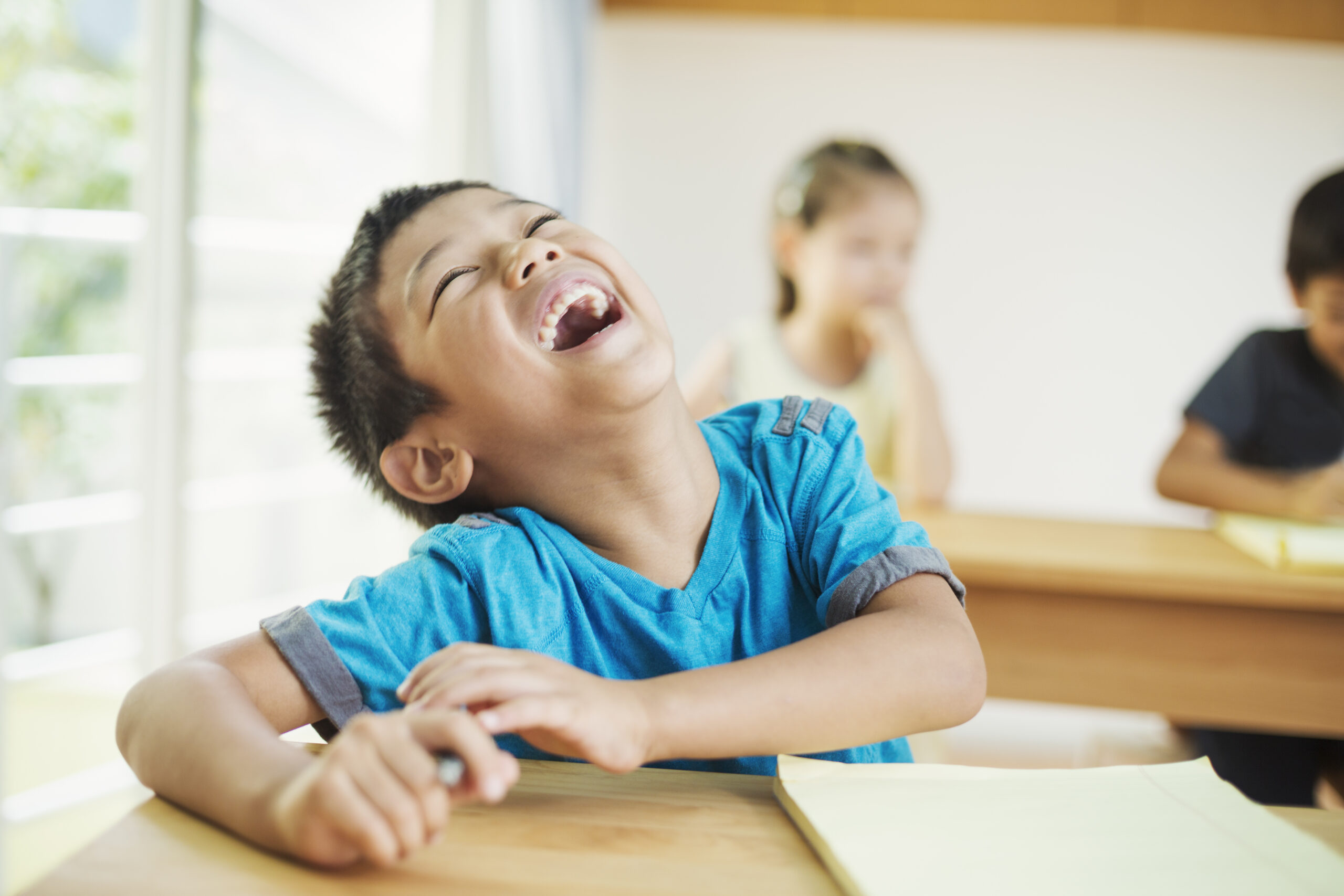 A group of children in school. ,fish tank kids,Japan A child smiling at a classroom desk