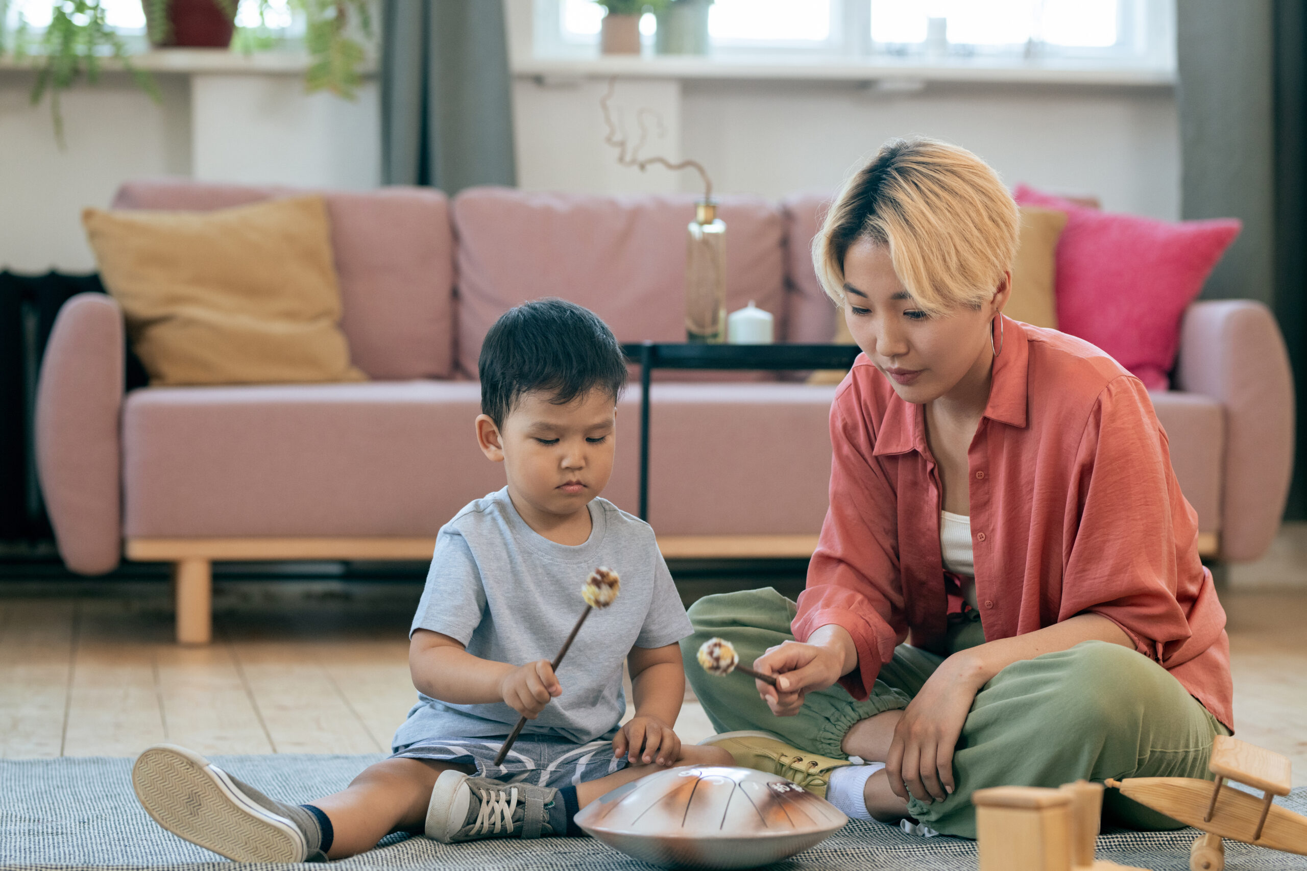 Young woman teaching her little son how to play handpan A child and adult playing music together