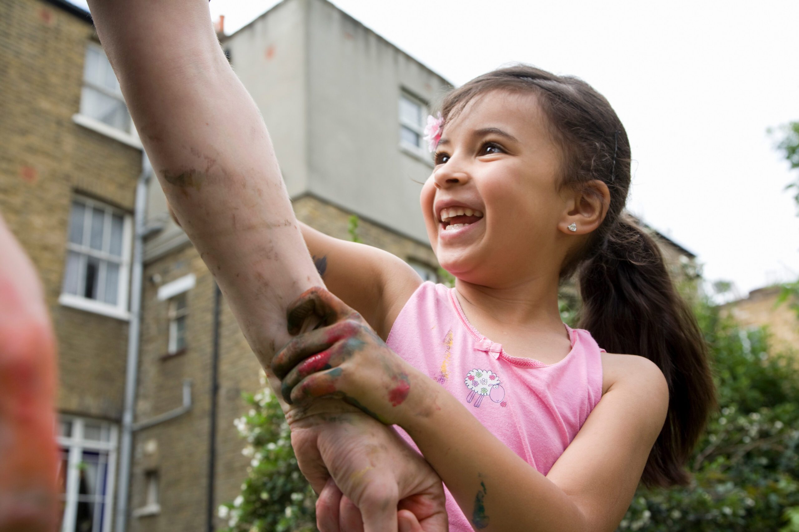 A child holding an adult’s arm outdoors