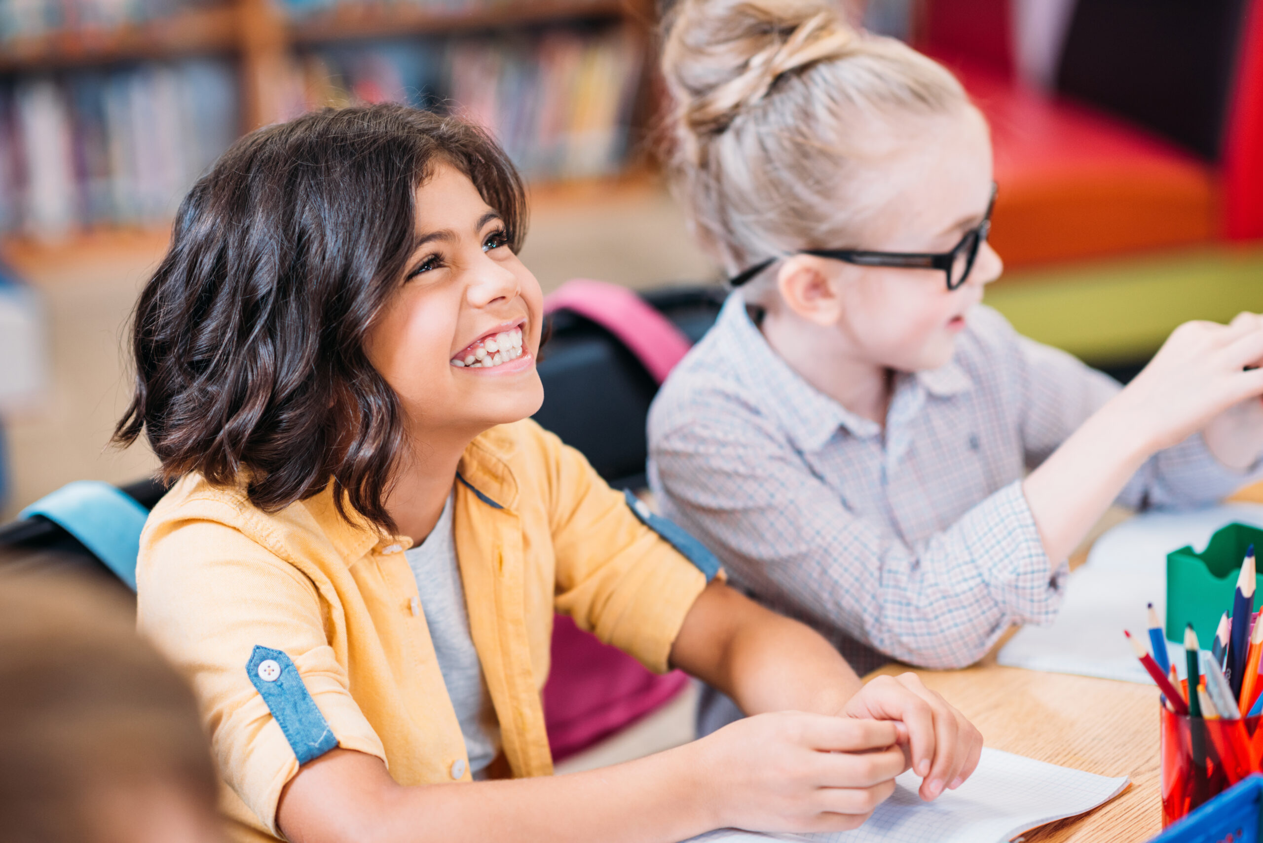 beautiful happy little girls in library Children studying together in a classroom