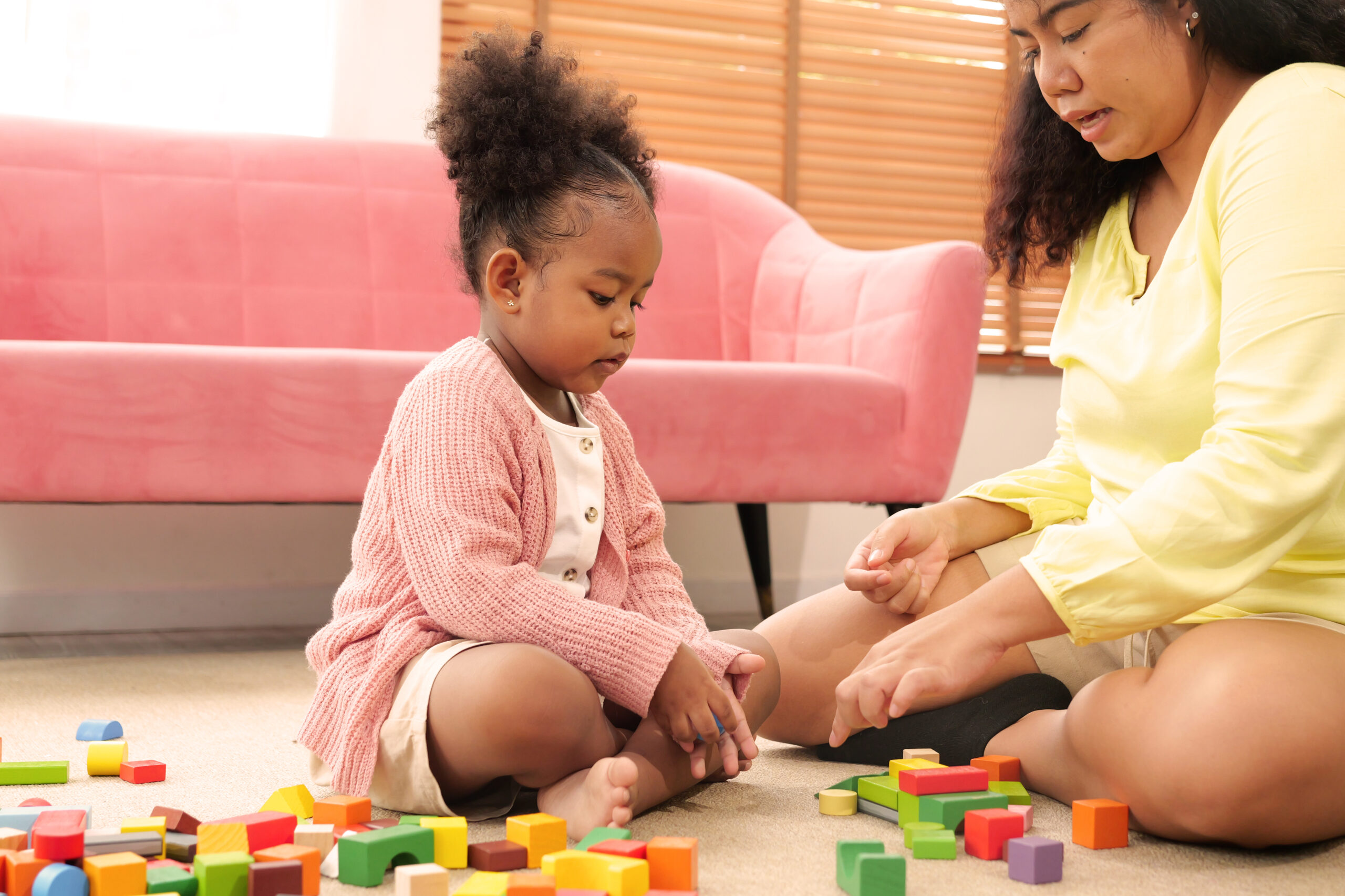 Happy mother spending time playing toys with daughter A child and adult playing with blocks